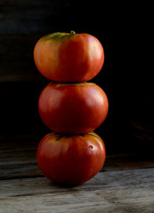Ripe red tomatoes stacked in an orderly manner on an old rustic table.