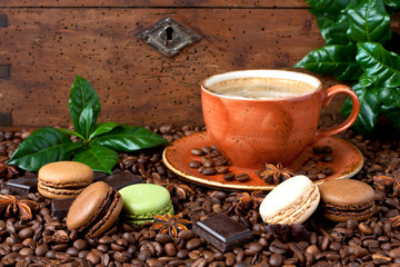 Cup of coffee with french macaroons cookies on dark  background.