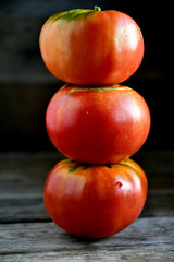 Ripe red tomatoes stacked in an orderly manner on an old rustic table.