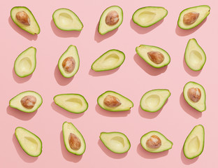 Avocados on pink background, flat lay avocado halves top view