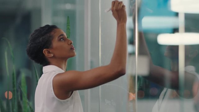 business woman writing on glass whiteboard female project manager brainstorming sales strategy using marketing data working late in office