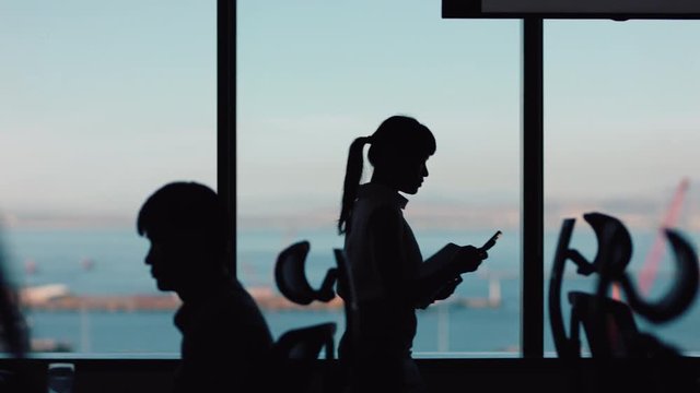 silhouette business woman using smartphone walking through office texting sending messages successful female executive checking emails on mobile phone in workplace