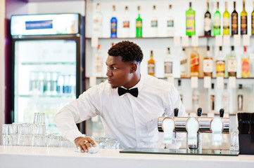 African american bartender wear on bow tie cleaning bar.