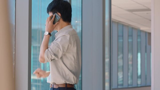 asian businessman using smartphone chatting to client financial advisor negotiating business deal corporate sales executive sharing expert advice having phone call in office looking out window