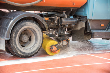 A big cleaning machine washes the running track with water stream