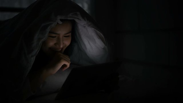 Communication concept. Women are playing tablets in the bedroom at night.