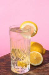 Fresh lemonade in a cocktail glass isolated on pink and purple background 