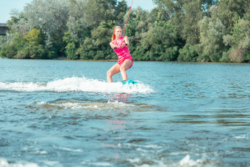 Young active beautiful blonde woman riding a wakeboard
