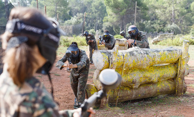 Obraz premium Group of opposite paintball players in camouflage with guns playing in battle