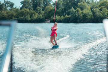 Smiling long-haired pretty young woman riding a wakeboard
