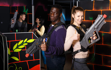 Two glad laser tag players standing back to back