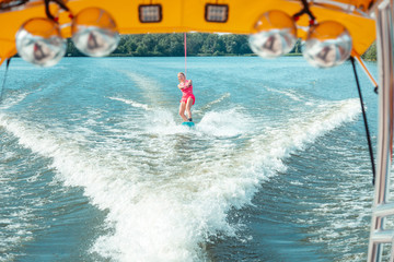 Young wakeboarder riding a wakeboard with eyes half-closed