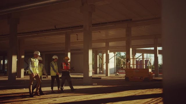 Diverse Team of Specialists Walk Through Garage Level of Industrial / Commercial Building Construction Site. Real Estate Project with Civil Engineer, Investor and Worker. Skyscraper Formwork Frames