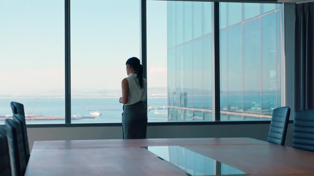 asian business woman using smartphone corporate sales executive chatting to client financial advisor negotiating deal sharing expert advice having phone call in office looking out window