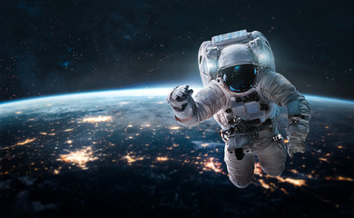 Astronaut in the outer space over the nightly planet Earth. City lights. Abstract wallpaper....