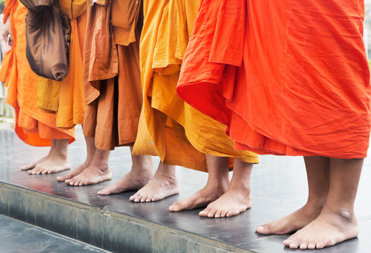 Low section of monk in traditional clothing standing on pavement