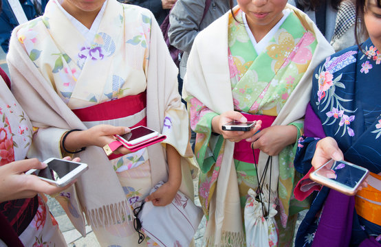 Women in kimono using smartphones outdoors