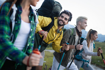 Fototapeta na wymiar Adventure, travel, tourism, hike and people concept - group of smiling friends with backpacks and map outdoors