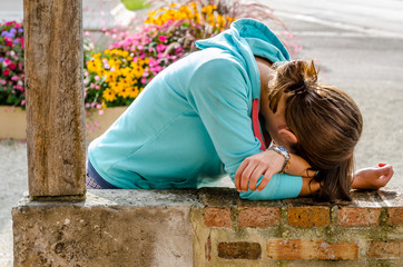 Young woman lying like crying on a stone wall