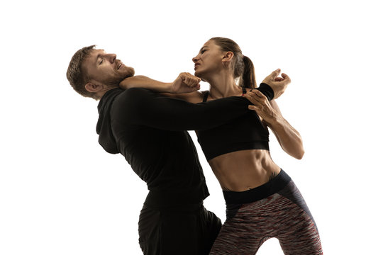 Man In Black Outfit And Athletic Caucasian Woman Fighting On White Studio Background. Women's Self-defense, Rights, Equality Concept. Confronting Domestic Violence Or Robbery On The Street.