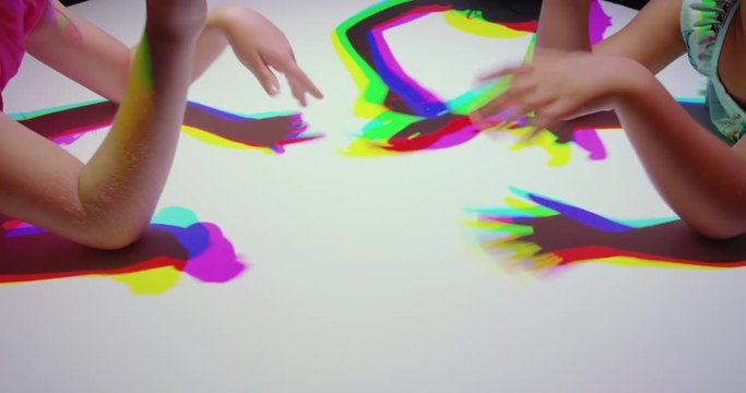 colorful hands of children having fun playing in multicolor light kids enjoying playful game with rainbow color silhouettes