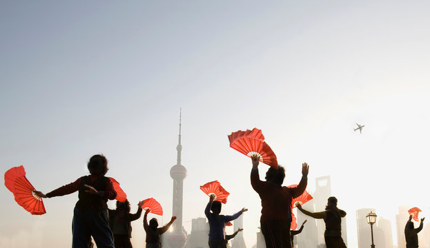 Group of women holding fans and dancing outdoors