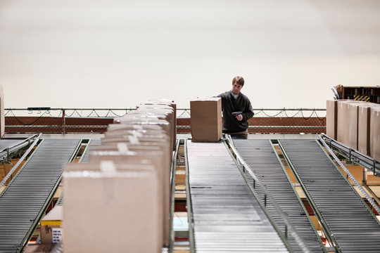 Man scanning cardboard boxes with barcode reader in distribution warehouse
