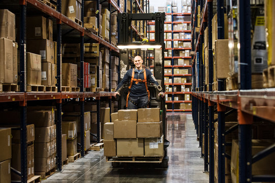 Portrait of man standing in stock picker loaded with cardboard boxes