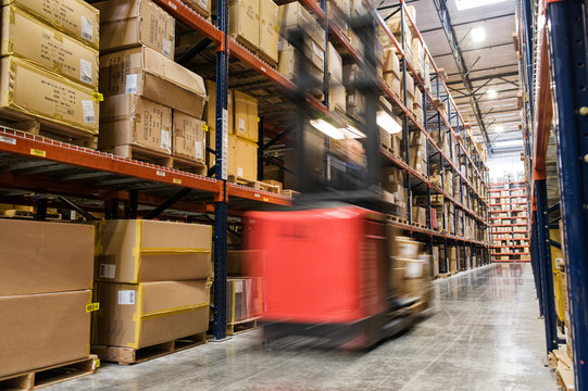 Blurred motion of stock picker moving between aisles of cardboard boxes
