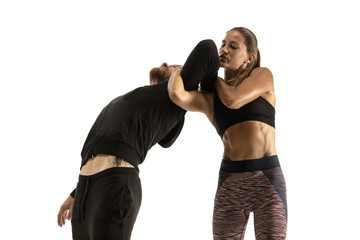 Man in black outfit and athletic caucasian woman fighting on white studio background. Women's...