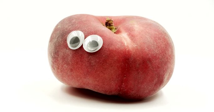 Donut peach with googly eyes on white background. Crazy funny fruit. Fruit face isolated rotation. Funny face rotates on itself.