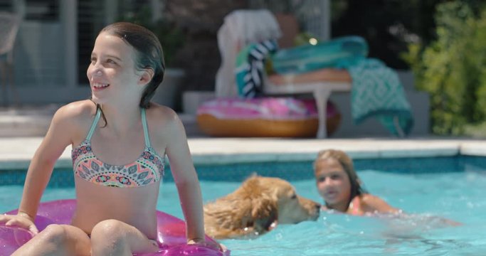 happy little girl in swimming pool floating on swim tube with playful dog having fun with kids enjoying summer day  on vacation 4k