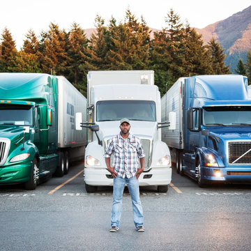 Portrait of truck driver standing near truck at truck stop