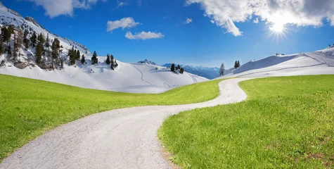Fotomontage Klimawandel, grüne Wiese mit Kurvenweg und Winterlandschaft im Gebirge und Sonnenschein © SusaZoom
