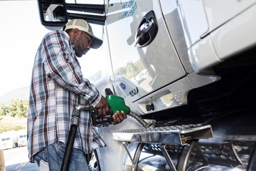 Side view of truck driver filling truck with diesel fuel at truck stop