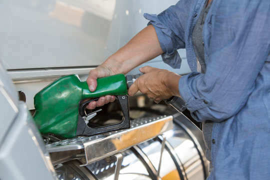 Midsection of truck driver filling truck with diesel fuel at truck stop