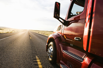 Commercial truck driving on road at sunset