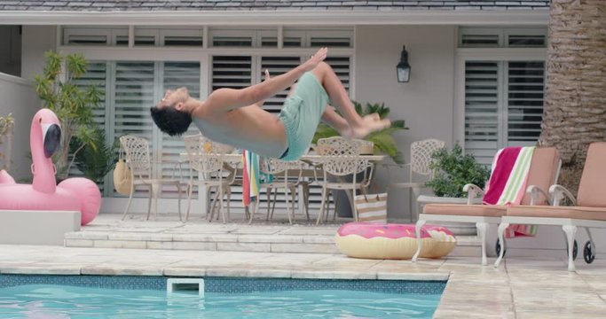 attractive young man jumping in swimming pool doing backflip splashing in water having fun summer day enjoying swim 4k