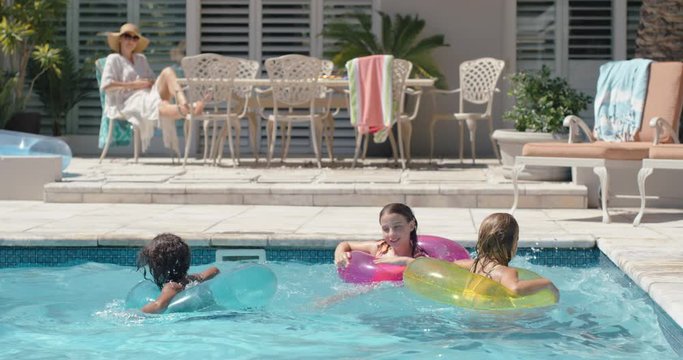 happy children swimming in pool with colorful swim tube inflatable toys kids splashing playfully having fun together on water floats enjoying summer vacation