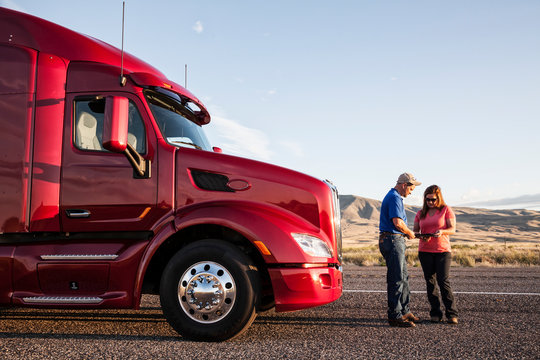 Couple checking their travel itinerary in front of commercial truck