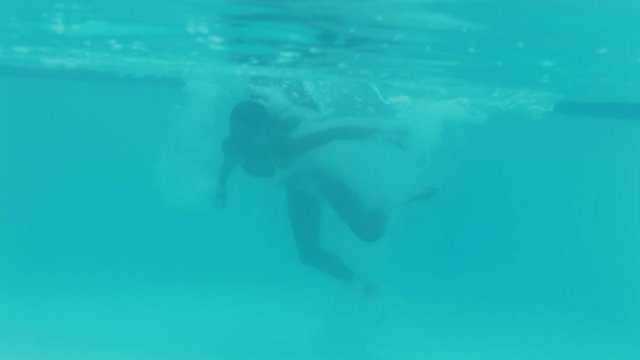 happy african american woman jumping in swimming pool splashing underwater having fun summer vacation enjoying summertime wearing yellow bikini 4k footage