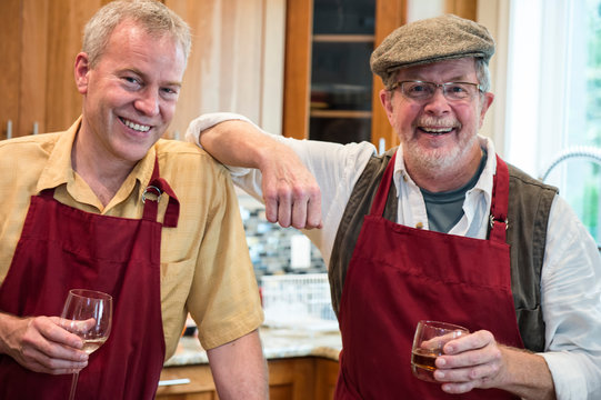 Portrait of smiling friends holding wine glasses in kitchen