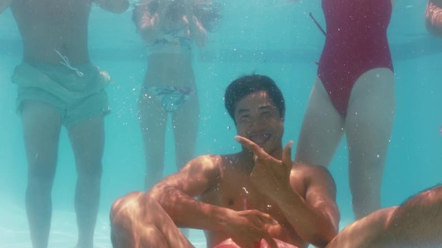 funny asian man swimming underwater in pool having fun with friends celebrating summer vacation together enjoying spring break pool party 4k