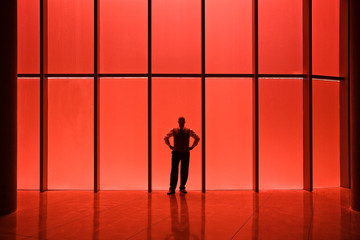 Businessman standing near red tinted window in office lobby