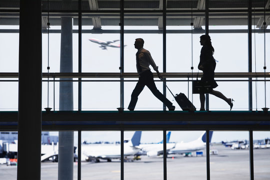 Businessman and businesswoman walking on walkway in airport