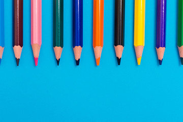 multicoloured pencils on blue background, back to scool concept.