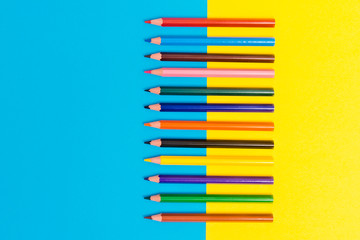Back to scool - Pencils detail. Colored sharp pencils detail in a row, isolated on blue and yellow.