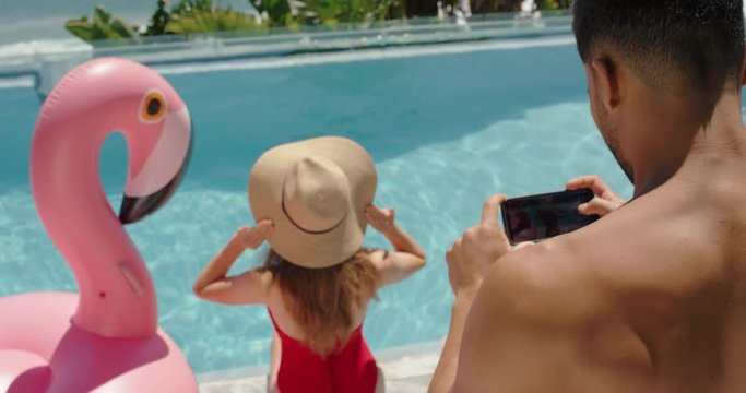 sexy woman model posing for photos by swimming pool photographer man using smartphone photographing female social media influencer on vacation at luxury hotel resort for summer bikini photoshoot