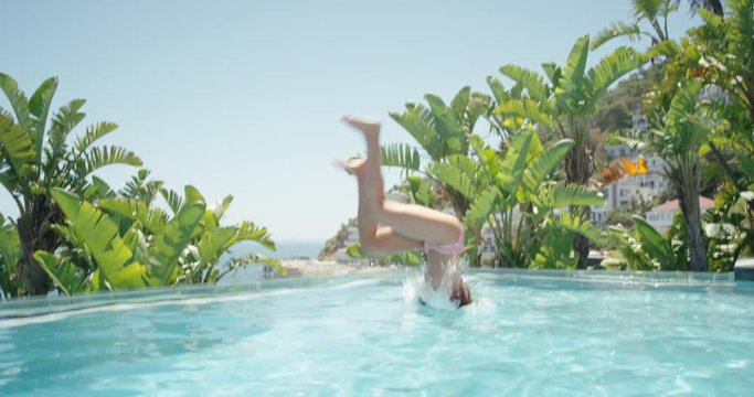 beautiful woman jumping in swimming pool doing backflip enjoying swim at tropical resort with ocean view having fun summer vacation on warm sunny day mediterranean travel 4k