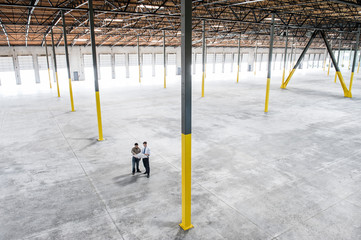 Architects talking over blueprint in warehouse
